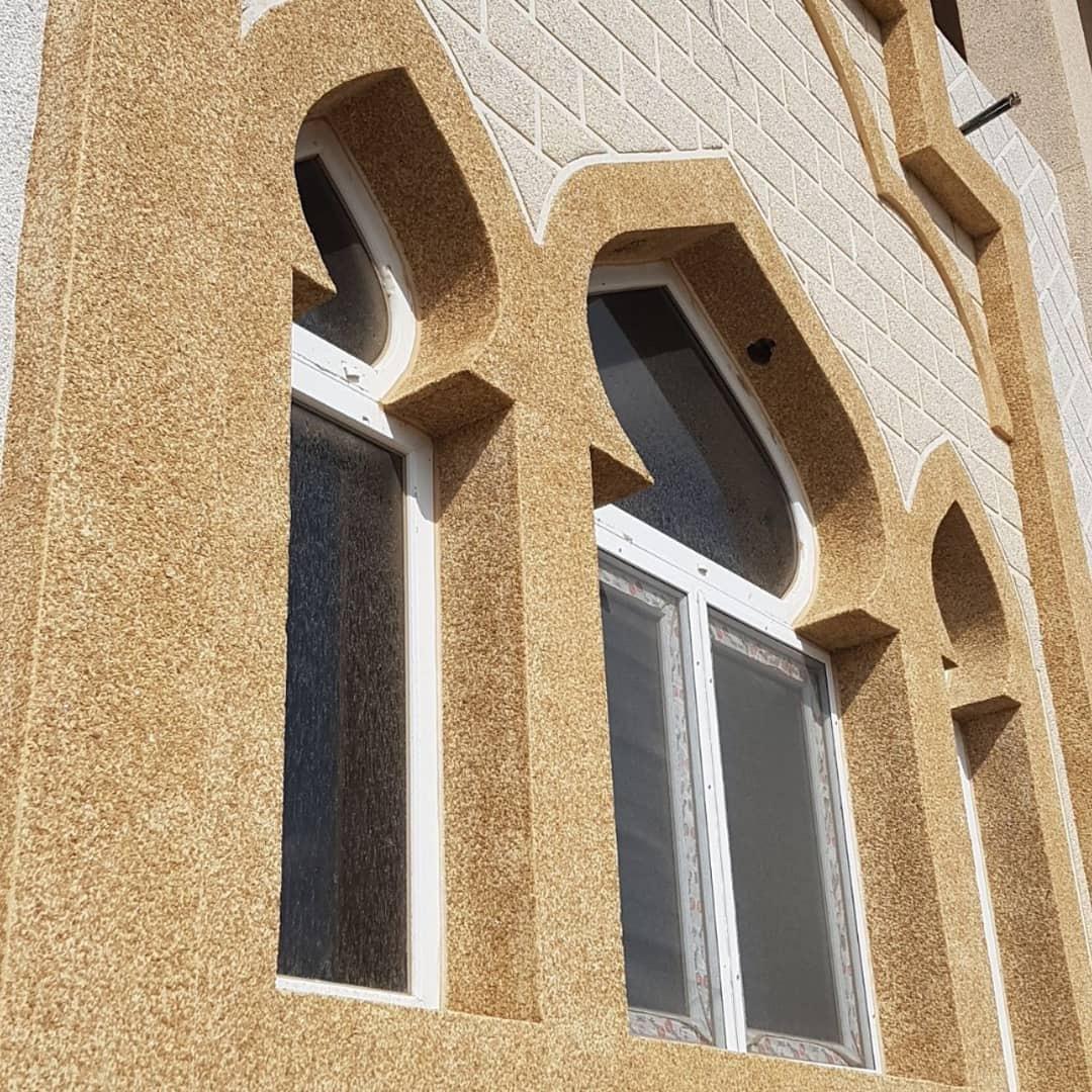 نوافذ مقوسة مكسوة بكسر الرخام الأصفر على واجهة كريمية